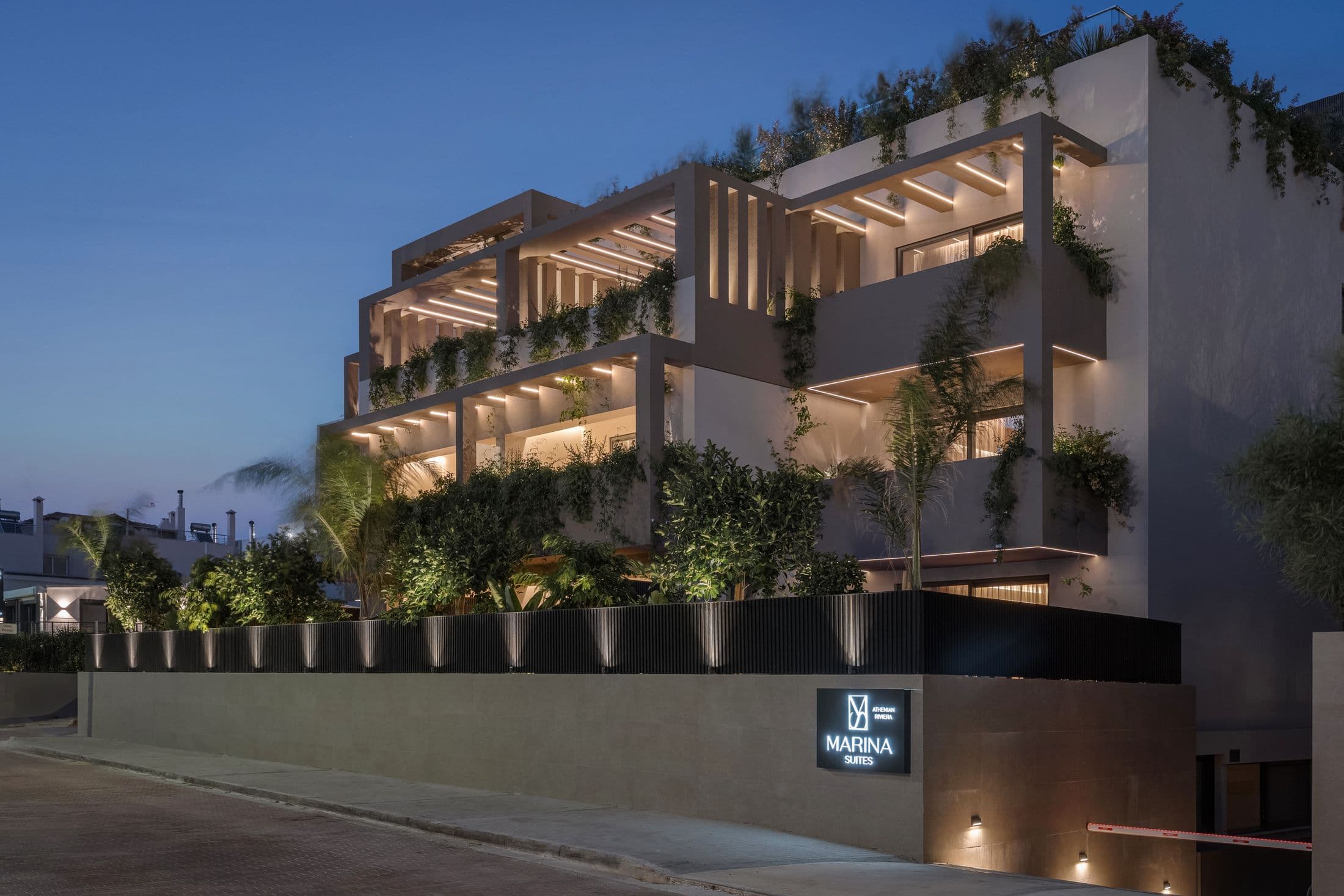 The Marina Suites building lit after dark, with its sign by the entrance